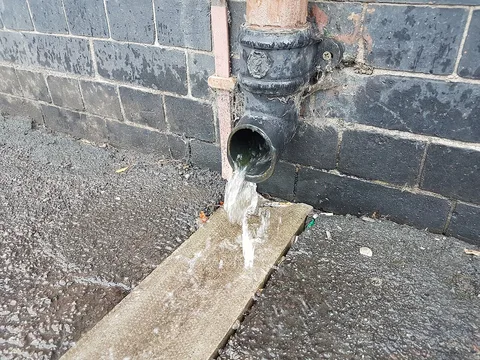 Descente d'eau qui déborde au pied d'un mur
